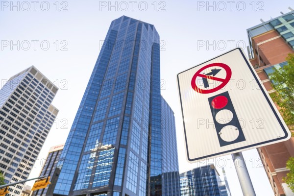 Low angle view of a no right turn sign and traffic light against towering modern skyscrapers in calgary, alberta, highlighting urban development and traffic regulations