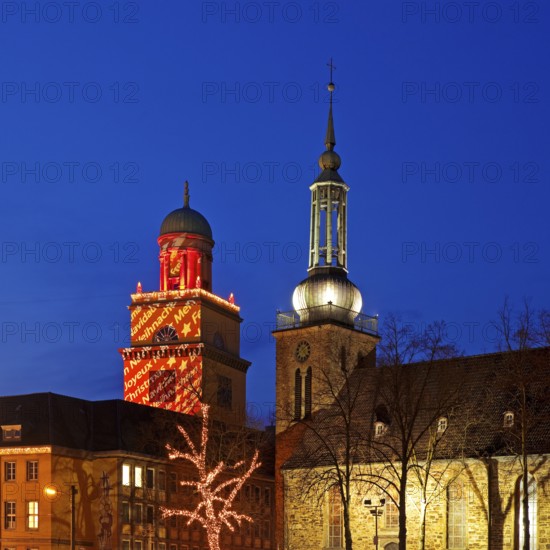 The Christmassy illuminated town hall tower and the illuminated church tower of St. John's Church in Witten, Ruhr area, North Rhine-Westphalia, Germany