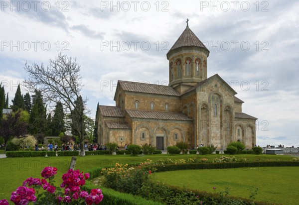 A historic church surrounded by a well-kept garden and blooming flowers under cloudy sky, Bodbe monastery, Sighnaghi, Signagi, Kakheti province, Greater Caucasus, Georgia, Western Asia