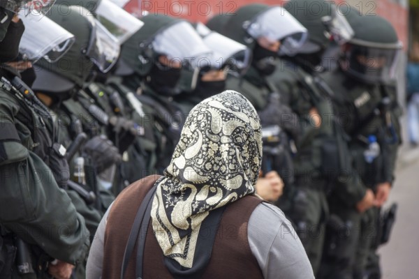 June 10, 2012 Demonstration in Göppingen, Baden-Württemberg, Germany. During a demonstration in an urban area, a woman wearing a headscarf walks past riot police officers accompanying the operation to ensure public order