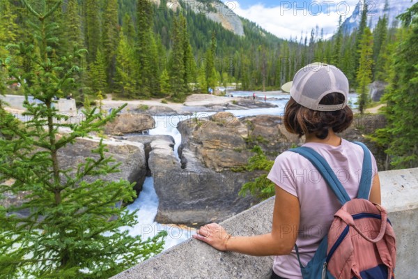 Female tourist with backpack enjoying the breathtaking view of the bow river natural bridge, a stunning rock formation in banff national park on a sunny summer day