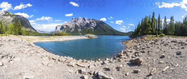 Turquoise waters of lake minnewanka reflecting surrounding mountains and forests in banff national park, creating breathtaking scenery on a clear summer day