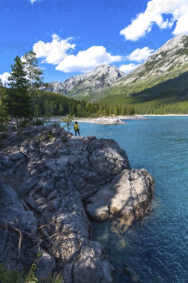 Tourist enjoying the stunning turquoise waters of lake minnewanka, surrounded by the majestic canadian rockies in banff national park on a beautiful summer day