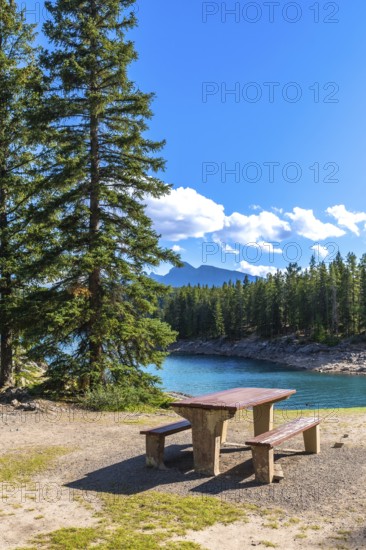 Turquoise waters of lake minnewanka sparkle under a bright blue sky, inviting visitors to enjoy a relaxing picnic amidst the breathtaking scenery of banff national park