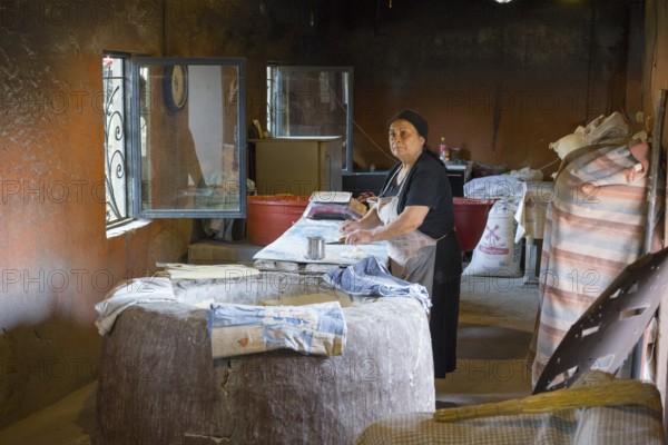 An elderly woman works in a traditional, rustic bakery with bread and baking supplies, bakery, Badiauri, Kakheti region, Georgia