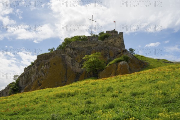 An old castle on a green hill under cloudy sky with a cross on top, Kveshi fortress, Bolnisi, Bolnissi, Lower Kartli region, Georgia