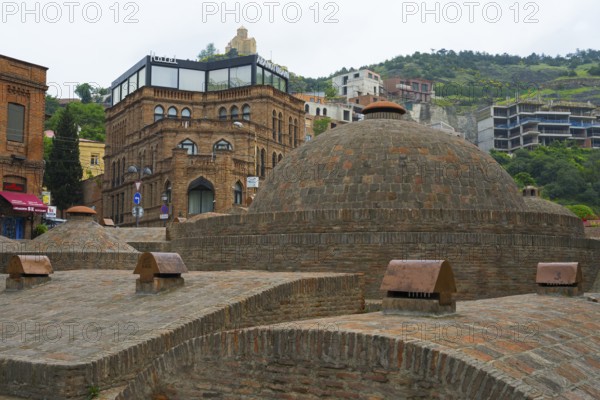 Historic brick buildings and urban baths in front of green hills, sulfur baths, Abanotubani spa district, old town, Tbilisi, Tbilisi, Georgia