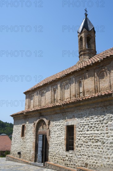Stone church with red tile roof and bell tower in sunny weather, Church of St. George, Old Town, Sighnaghi, Signagi, Kakheti Province, Greater Caucasus, Georgia, Western Asia