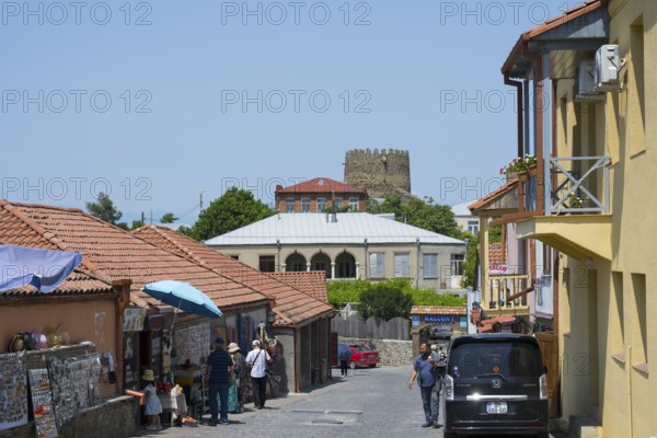 Urban street scene with people, red roofs and castle in the background, old town, Sighnaghi, Signagi, Kakheti province, Greater Caucasus, Georgia, Western Asia