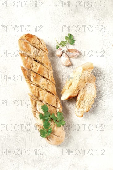 Garlic bread, baguette with garlic butter and herbs, on a light table, top view