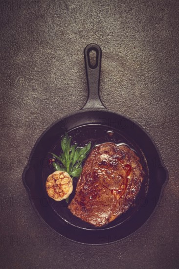 Grilled rib eye steak, in a cast-iron skillet, top view, homemade, no people