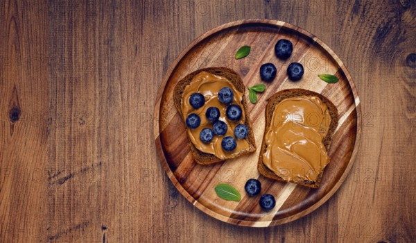Rye bread with peanut paste and fresh blueberries, top view, no people