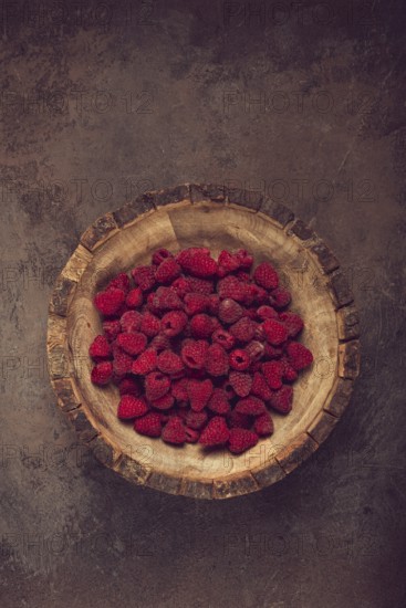 Fresh raspberries in a wooden bowl, food background, concept, food styling, on a dark table, top view, no people
