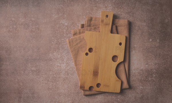 Wooden cutting board, rectangular with handle, cheese shape with holes, on a kitchen towel, top view, food background, no people