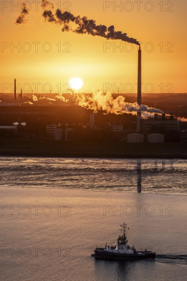 Fairplay 61 harbour tug arrives at the mouth of the Weser, in the background the Kronos Titan chemical plant, a leading global manufacturer of titanium dioxide, in Nordenham, Bremerhaven, sunset, Germany