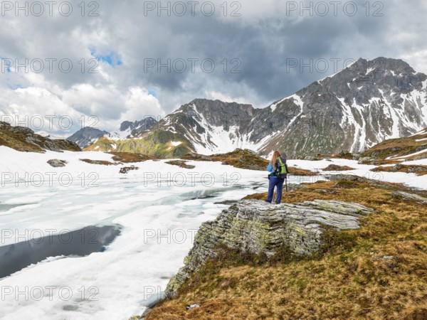 Half-frozen mountain lake with hiker, snow, Essersee, Stierkarkopf, Wildkarhöhe and Rothorn, Radstädter Tauern, Riedingtal nature park Park, Zederhaus, Lungau, Salzburg
