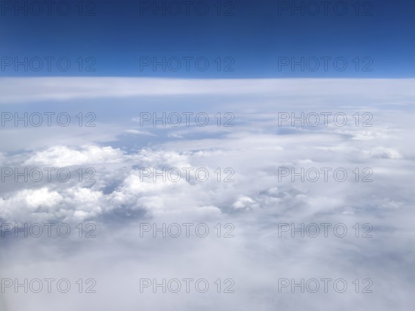 View from an airplane of closed cloud cover in it white bright cluster clouds cirrus clouds on the left, international
