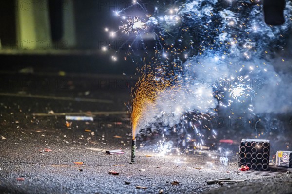 Burnt off fireworks are lying on the street, firecracker smoke produces smoke. New Year's night on a street in Stuttgart, Baden-Württemberg, Germany