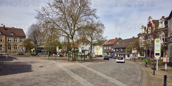 Niedersprockhövel bus stop church, bus platform, general architecture, houses, residential buildings and commercial buildings, bare winter trees, barrier bollards, cars, slightly diffused light, slightly sunny, milky blue sky, cumulus clouds, cirrostratus clouds, street main street, Sprockhövel, Ennepe-Ruhr district, North Rhine-Westphalia, Germany
