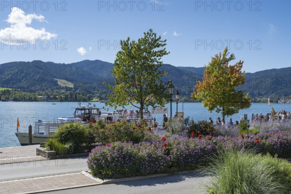 Jetty at Tegernsee, tourists on the promenade, flower beds in the foreground, town of Tegernsee, Upper Bavaria, Bavaria, Germany