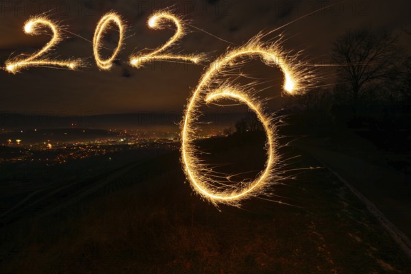 New Year's Eve atmosphere in Stuttgart at the turn of 2025 to 2026: In the foreground, a painted number 2026, written with a glowing sparkler as a symbol of a new beginning and celebration