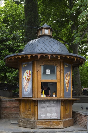 Traditional wooden kiosk with ice cream advertising surrounded by trees in an urban park, antique kiosk, Tbilisi, Tbilisi, Georgia