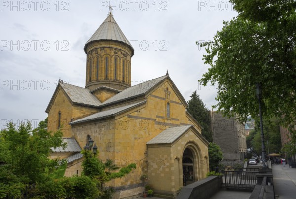 Historic church with yellow stone architecture and dome surrounded by trees on a cloudy day, Sioni Cathedral, Tbilisi, Tbilisi, Georgia