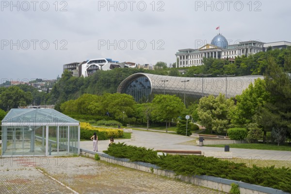 Glass-covered architecture in a park with green spaces, Rike Music Theatre and Exhibition Center, behind it State Palace for Ceremonies, Avlabari Residence or Presidential Palace, Tbilisi, Georgia