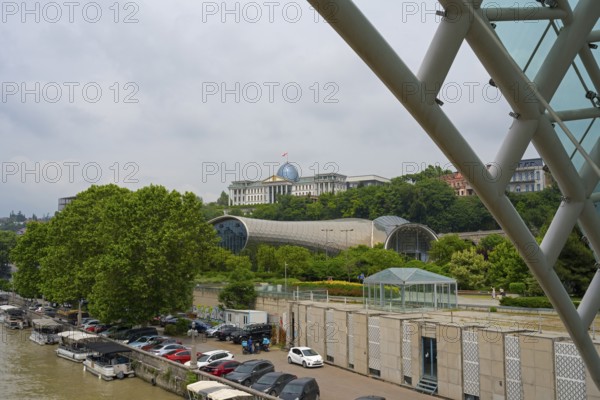 View from the riverbank of modern buildings and dome with boats in the foreground, view from the Peace Bridge of Rike Music Theatre and Exhibition Center, behind it State Palace for Ceremonies, Avlabari Residence or Tbilisi Presidential Palace, Tbilisi, Kura River, Georgia