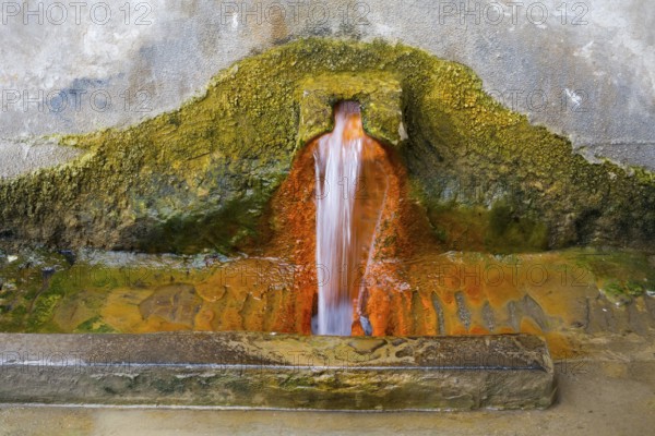 Rust-brown water flows from a spring in a concrete wall surrounded by eroded mineral deposits, mineral spring, Bolnissi, Katharinenfeld, Lower Kartli region, Kwemo Kartli, Georgia