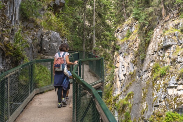 Mother and children enjoying the breathtaking views while walking along the scenic catwalks of johnston canyon in banff national park, alberta, canada, surrounded by lush forest and rocky cliffs