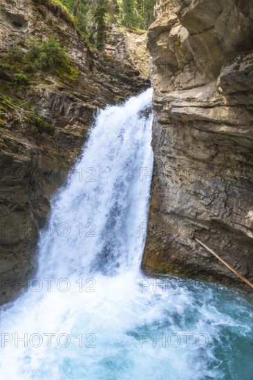 Powerful waterfall plunging into a vibrant turquoise pool in johnston canyon, creating a breathtaking spectacle of nature's beauty in banff national park, canadian rockies, alberta, canada