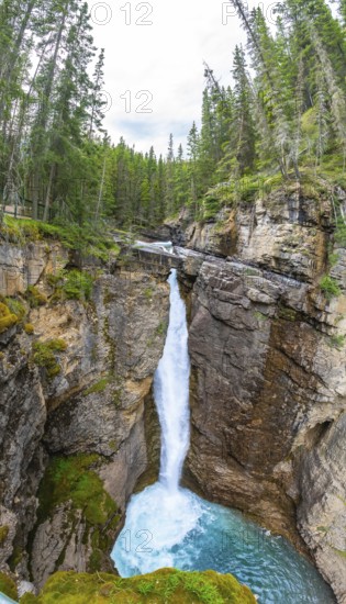 Breathtaking waterfall cascading into a vibrant turquoise pool amid the rugged beauty of johnston canyon in banff national park, alberta, canada