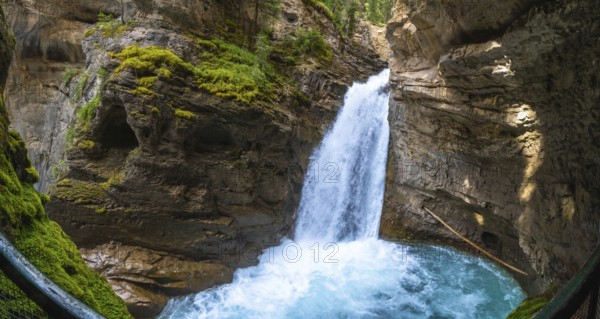 Sunlight illuminating the vibrant turquoise pool at the base of a cascading waterfall in johnston canyon, banff national park, showcases breathtaking natural beauty