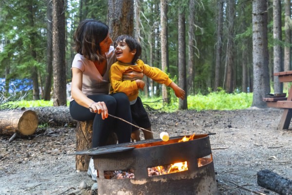 Mother and son are roasting marshmallows over a campfire in banff national park, alberta, canada, enjoying quality time together in the beautiful natural setting