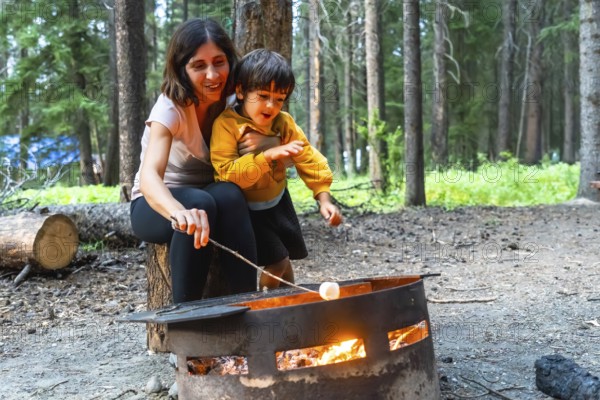 Mother and son roasting marshmallows over a campfire in banff national park, alberta, enjoying a camping trip amidst the beautiful canadian rockies