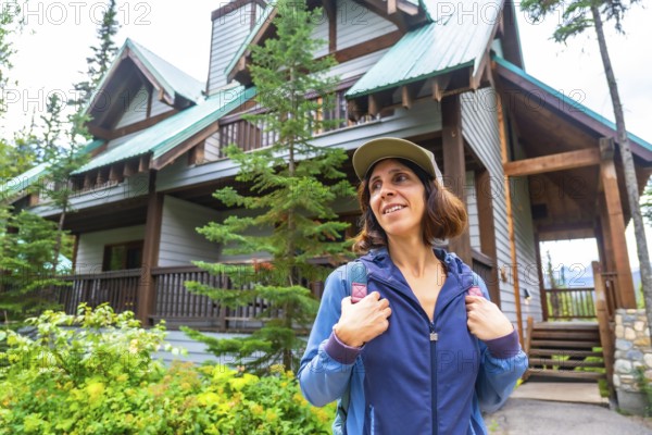 Female tourist wearing a baseball cap and backpack is arriving at emerald lake lodge in yoho national park, british columbia, canada, enjoying the beautiful scenery