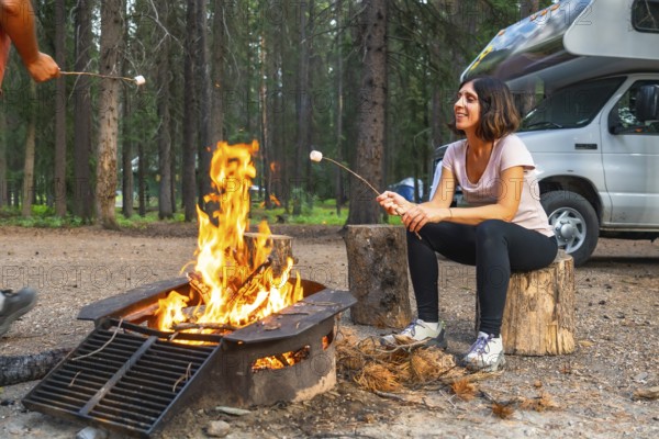 Tourists are roasting marshmallows over a campfire near their campervan in banff national park, canadian rockies, alberta, enjoying a relaxing evening in nature