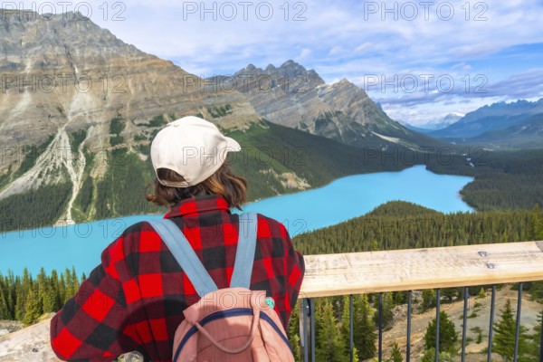 Female hiker enjoying breathtaking view of turquoise peyto lake and surrounding mountains in banff national park, canadian rockies, alberta, canada, during summer day