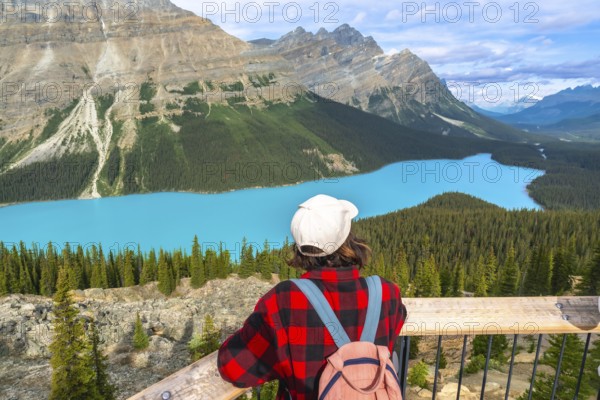 Tourist with a backpack enjoying breathtaking views of vibrant turquoise waters at peyto lake, surrounded by the majestic canadian rockies in banff national park