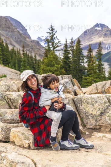 Mother and son sitting on rocks, soaking in the stunning views of turquoise peyto lake and surrounding mountains in banff national park, creating lasting memories