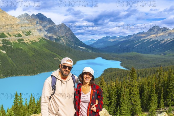 Two hikers enjoying the breathtaking panoramic view of turquoise peyto lake, surrounded by the majestic canadian rockies in banff national park on a sunny day