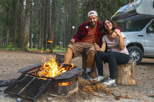 Tourists roasting marshmallows in banff national park, alberta, enjoying a cozy evening by the campfire next to their campervan, surrounded by the serene beauty of the canadian rockies