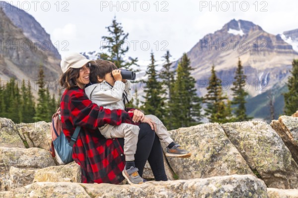 Mother and son are enjoying a scenic view at peyto lake in banff national park, with the boy using binoculars to observe the surrounding mountains and nature