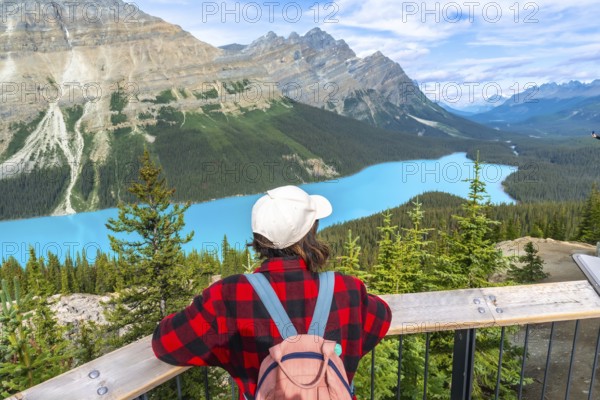 Female tourist with a backpack admiring the stunning turquoise waters of peyto lake, framed by the majestic canadian rockies in banff national park, alberta