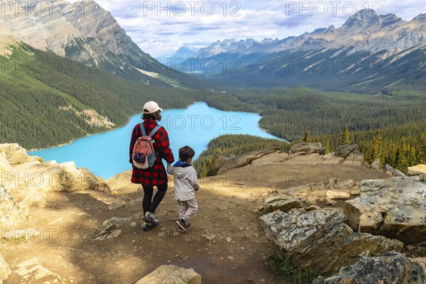 Mother and child admiring the stunning turquoise waters of peyto lake from a scenic viewpoint in banff national park, alberta, on a beautiful summer day