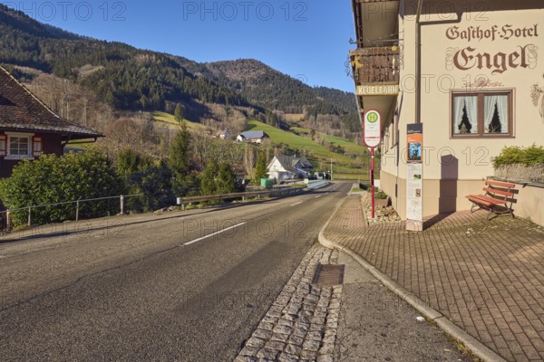 Simonswald Engel bus stop, Gasthof Hotel Engel, buildings, general architecture, landscape, hilly landscape, hills, coniferous forest, road, center line, sidewalk, guardrail, blue sky, cloudless, Obertalstraße, Simonswald, Black Forest, Emmendingen district, Baden-Württemberg, Germany