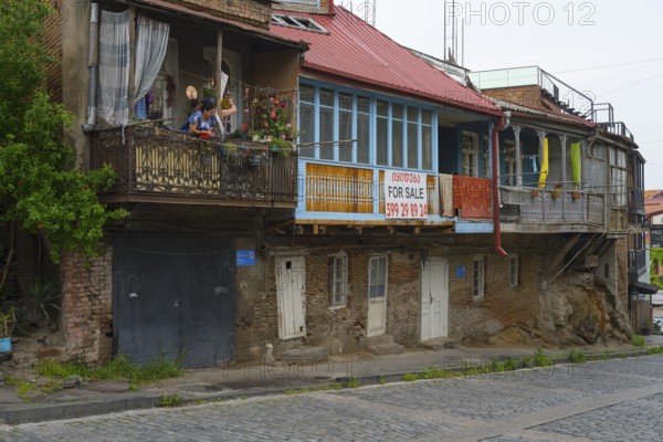 Dilapidated residential buildings with sales signs and rustic balconies on a paved street, Old Town, Tbilisi, Tbilisi, Georgia