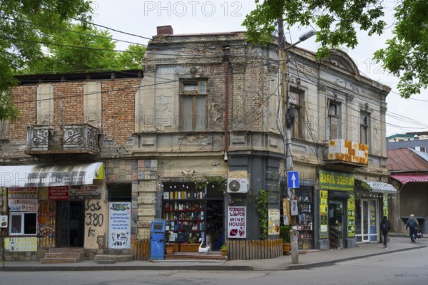 An old building corner with shops on the street, surrounded by trees and power lines, Tbilisi, Tbilisi, Georgia