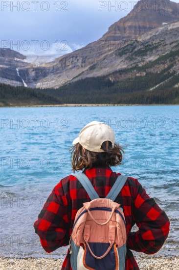 Female hiker with backpack enjoying breathtaking view of turquoise bow lake and crowfoot glacier in banff national park, canadian rockies, alberta, canada, promoting tourism and outdoor adventure